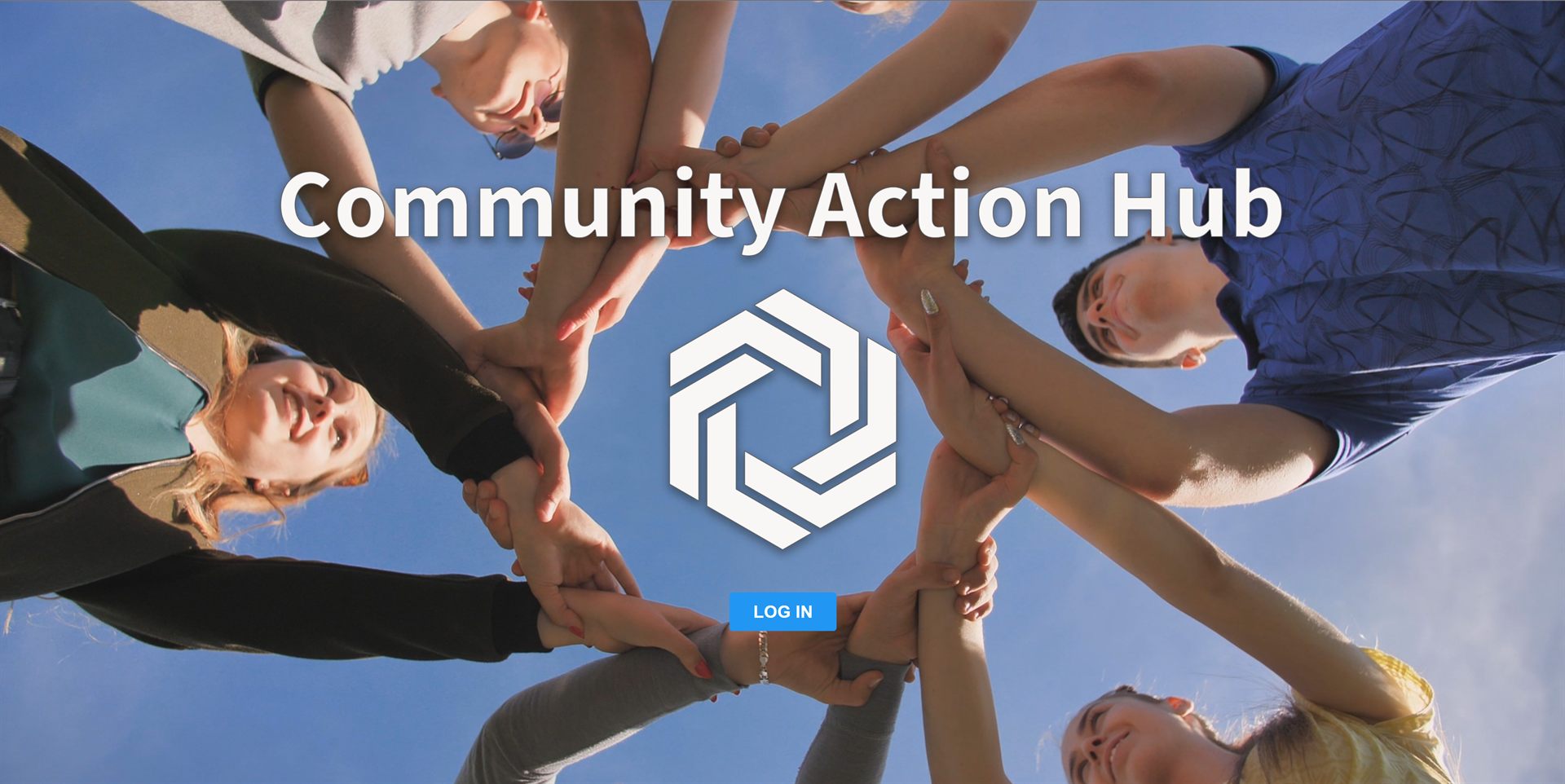 The Community Action Hub sign-in screen: the product name and hexagonal logo over a photograph of people standing in a circle with their hands joined, and a single log in button.